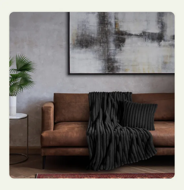 A dark-colored throw placed on a sofa