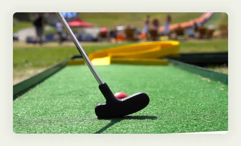 Trade show visitor putting golf ball on miniature putting green setup